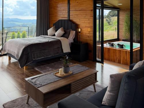 a bedroom with a bed and a view of a tub at Cabañas El Abuelo in La Calera