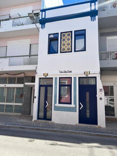 a white building with blue doors on a street at Dolce Faro Niente Guest House in Faro