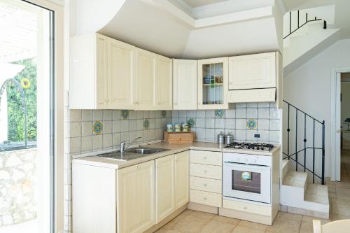 a kitchen with white cabinets and a sink at Villa Claudia - YourPlace Abruzzo in Termoli