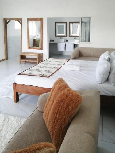 a bedroom with a large bed and a couch at Duna Serena Tiny Houses in Praia do Tofo