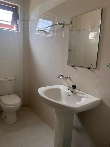 a white bathroom with a sink and a toilet at Dissanayaka house in Nikawatawana