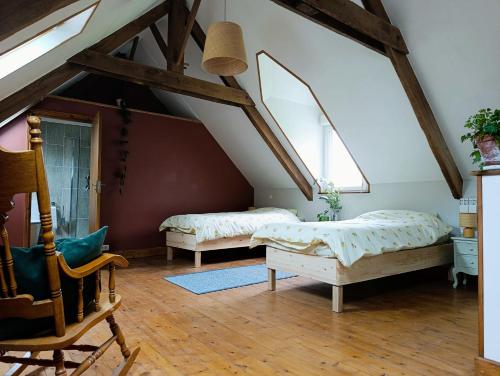 a attic bedroom with two beds and a chair at Les champs sauvages in Saint-Barnabé