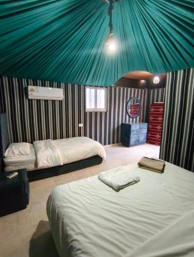 a bedroom with two beds and a green tent at Sand Rose Camp - Wadi Rum in Wadi Rum