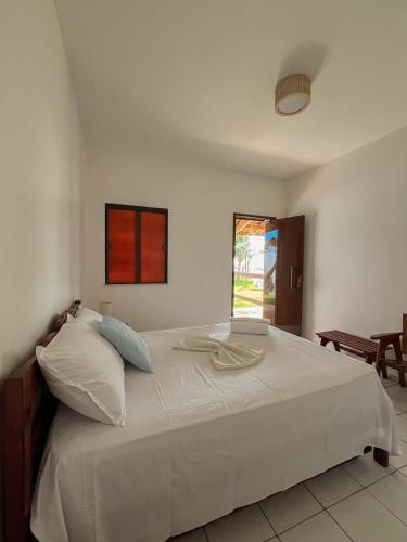 a bedroom with a large white bed with a window at Pousada Recanto da Mãezinha in Beberibe