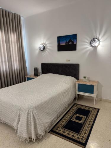 a bedroom with a white bed and a nightstand and a bed sidx sidx sidx at Résidence central 1 in Nabeul