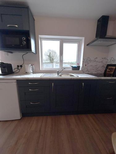 a kitchen with black cabinets and a sink and a window at Meadow View in Birr