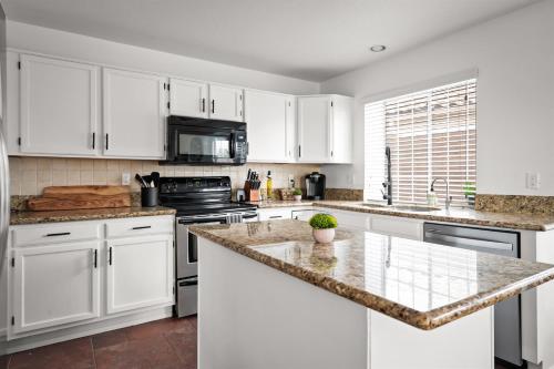 a kitchen with white cabinets and a granite counter top at Heated Pool 3BR Retreat Estrella Mountain in Goodyear