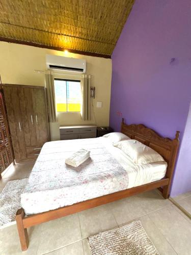 a bedroom with a large bed with a purple wall at Loft com vista Panoramica in Paraty