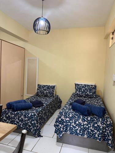 two beds in a room with blue pillows at Centro de Alfenas Térreo Completo in Alfenas