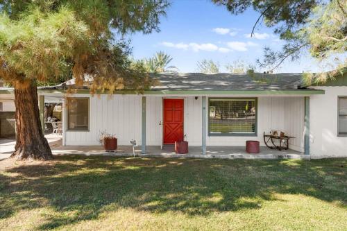 a white house with a red door and a tree at Charming 2-BR Farmhouse Backyard Views in Mesa