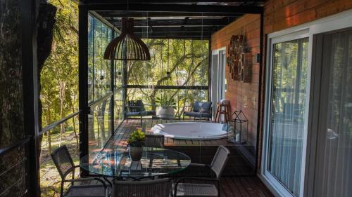 a screened in porch with a table and a tub at Vila Nambu - Exclusive Pousada in Gramado