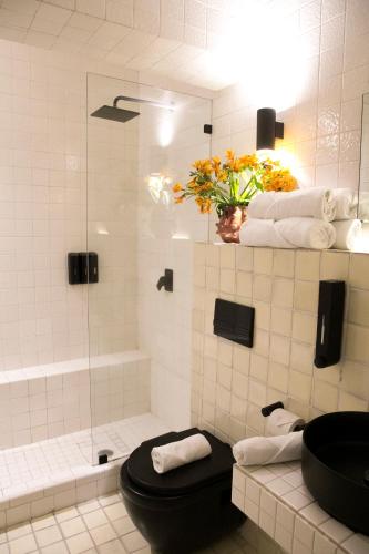 a bathroom with a toilet and a shower with a vase of flowers at Casa JuliAna in Mexico City