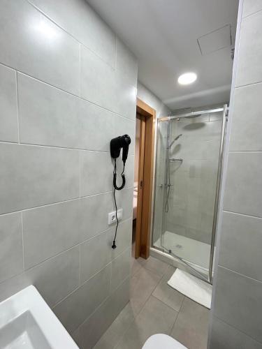 a bathroom with a shower and a phone on the wall at Be Ramblas Guest House in Barcelona