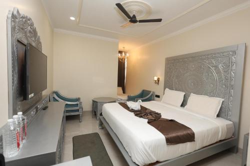a bedroom with a large bed and a flat screen tv at Hotel Shringar Mahal Vrindavan in Chhatikara