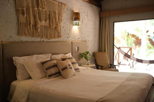 a bedroom with a bed with white sheets and pillows at Pousada Aldeia da Serra in Palmas