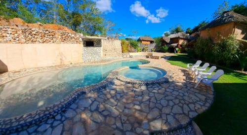 a swimming pool in a yard with white chairs at Cabañas Aldea Yalcón in Valladolid