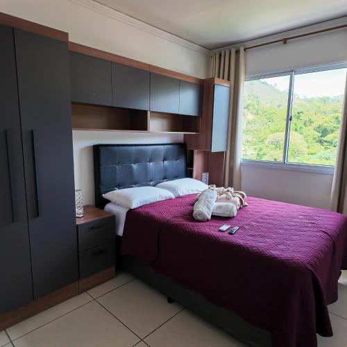 a bedroom with a large bed with a purple blanket at Apartamento luxo, há 5min do centro de Itaipava in Petrópolis