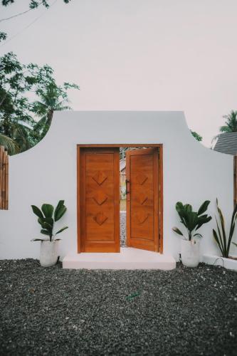 a door in a white building with two potted plants at Green Waves Villa in Batukaras