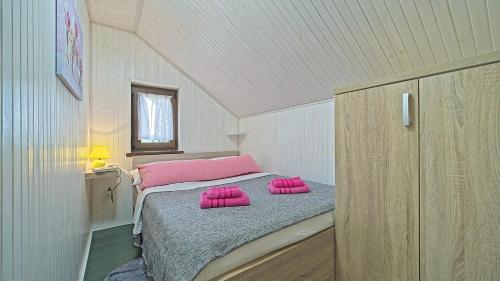 a small bedroom with pink pillows on a bed at House Kiki by Villas Guide in Bosiljevo