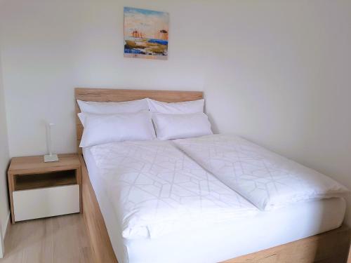 a bed with white sheets and pillows in a bedroom at Apartma Dana in Jadranovo