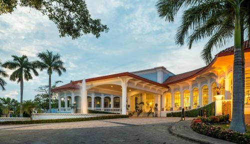 a building with palm trees in front of it at Quinta Edén Villahermosa in Villahermosa