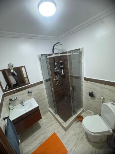 a bathroom with a shower and a toilet and a sink at Résidence Al kawtar, Mimosa Appartement in Ben Slimane