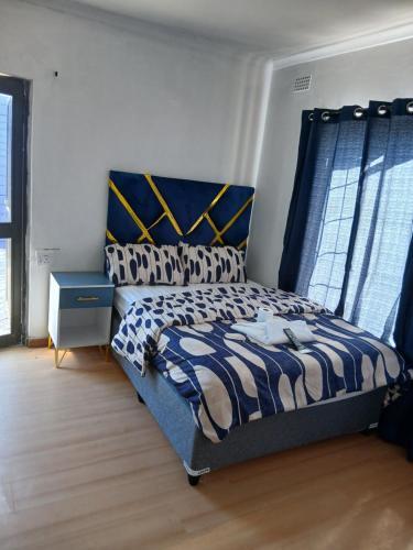 a bedroom with a bed with a blue and white comforter at Tatami Guesthouse in Parow