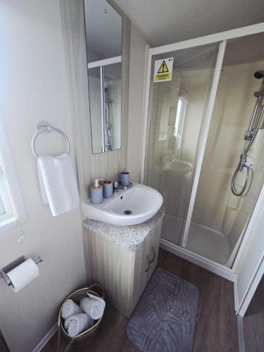 a bathroom with a sink and a shower at Barmouth wave - Sunnysands Holiday Park caravan in Llanddwywe