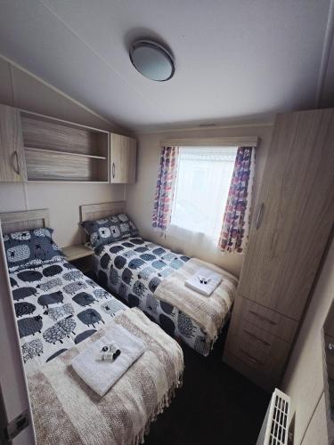 a bedroom with two beds and a window at Barmouth wave - Sunnysands Holiday Park caravan in Llanddwywe
