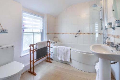 a white bathroom with a tub and a sink at 3 Bed in Porthleven oc-harbli in Porthleven