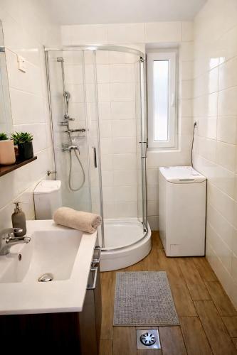 a white bathroom with a shower and a sink at Apartment Drejca in Kobarid