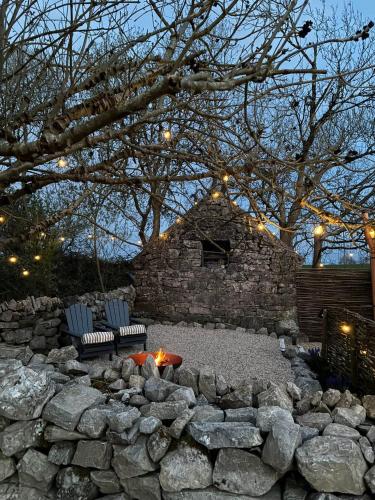 a stone wall with two chairs and a fire pit at Shepherds Hut Galway in Galway