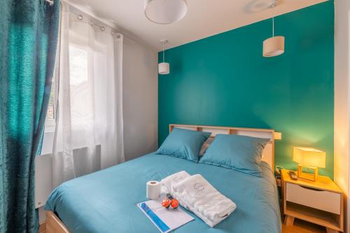 a blue bedroom with a bed with towels on it at Appartement la Perle in Ambérieu-en-Bugey