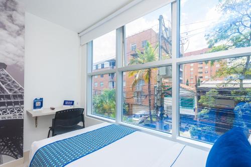 a room with a large window with a bed and a desk at Hotel Laureles Plaza in Medellín