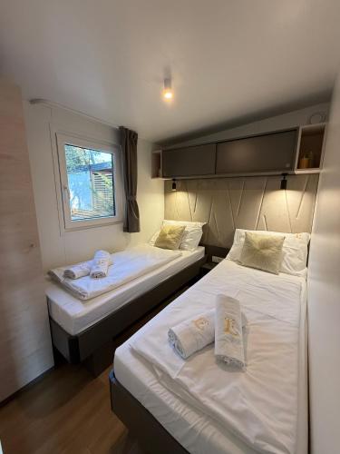 two beds in a small room with a window at GoLD mobile homes D&L in Biograd na Moru