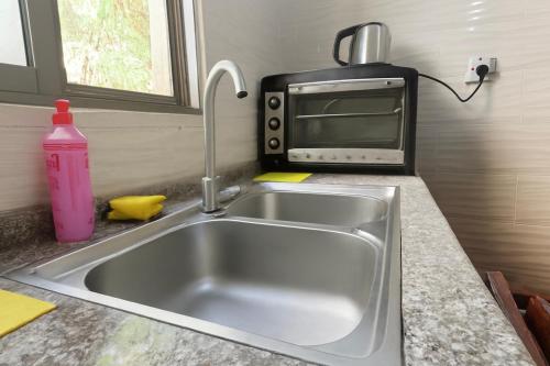 a kitchen sink with a toaster oven and a microwave at CozyQ Apt in Aqaba