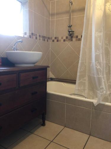 a bathroom with a sink and a bath tub with a sink at Knowles Nook Self-catering in Klerksdorp