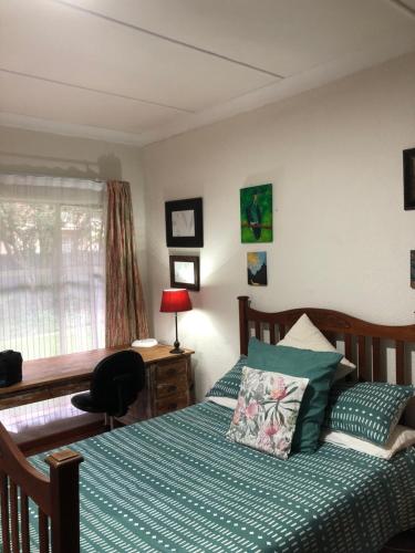 a bedroom with a bed and a desk and a window at Knowles Nook Self-catering in Klerksdorp