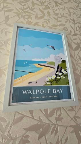 a picture of a beach with a sign on a wall at Amazing Beachside 2BD Family Home with Garden in Cliftonville