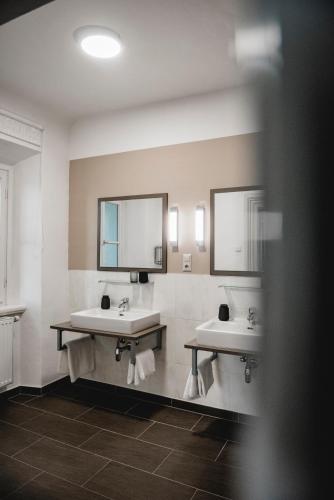 a bathroom with two sinks and two mirrors at KOKORO am Kirchplatz in Sankt Veit am Vogau