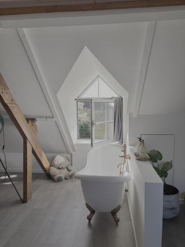 a white bathroom with a bath tub and a window at Bij Liezeke in Zemst