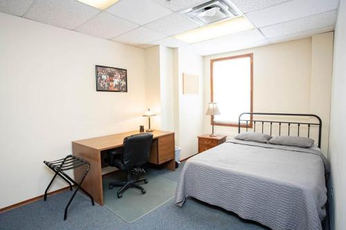 a bedroom with a bed and a desk and a computer at Wardens Quarters: 2 Bedroom Apt in Sault Ste. Marie