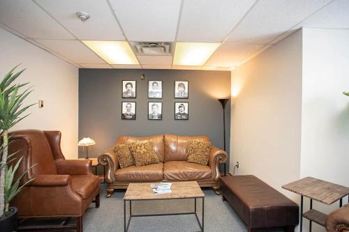 a waiting room with a leather couch and chairs at Wardens Quarters: 2 Bedroom Apt in Sault Ste. Marie