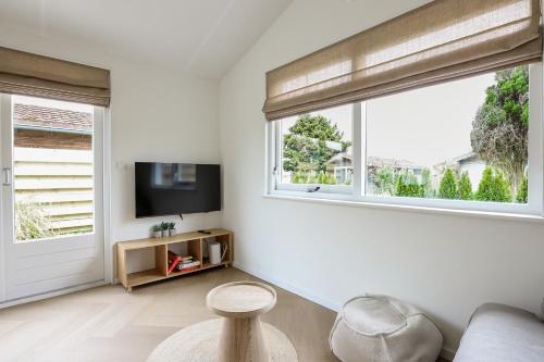 a living room with a couch and a tv and two windows at Rekerlanden 270 in Warmenhuizen