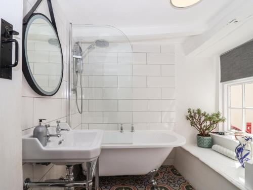 a white bathroom with a tub and a sink at Cousham Cottage in Cawsand
