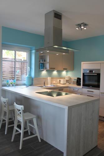 a kitchen with a counter with two chairs and a sink at Ferienhaus Oberhüs - Das Familien-Ferienhaus an der Ostsee in Scharbeutz