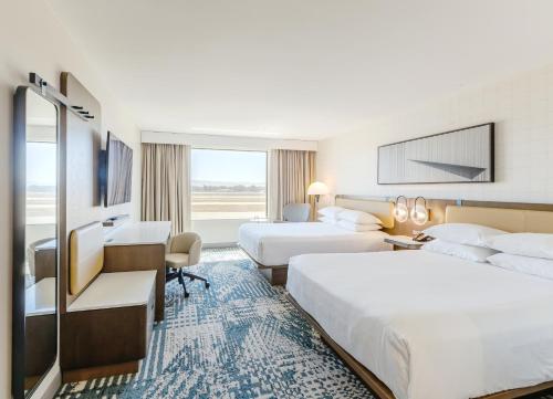 a hotel room with two beds and a desk at Radisson Hotel Santa Maria in Santa Maria