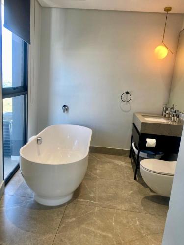 a bathroom with a tub and a toilet and a sink at Elegant-World Ellipse Waterfall in Midrand