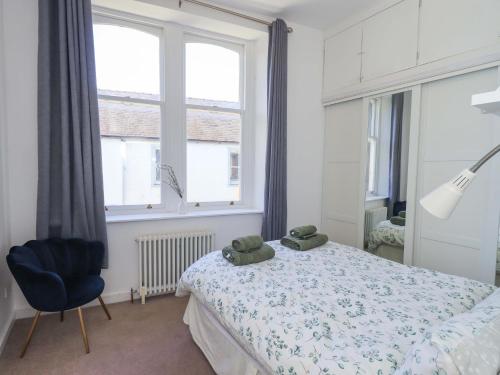 a bedroom with a bed with a blue chair and a window at St Johns View in Keswick