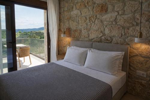a bedroom with a bed and a stone wall at Aria Vista Chalkidiki in Agios Nikolaos